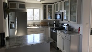 A modern kitchen with a central island, stainless steel appliances, and white cabinetry. - Waterfront Keuka Lake INCREDIBLE VIEWS • BOAT SLIP • TWO BALCONIES 3rd floor (Hammondsport)