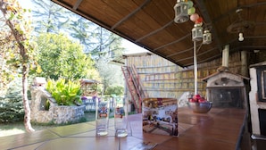 Un espacio al aire libre cubierto con un muro de piedra, una mesa de madera y un cartel.