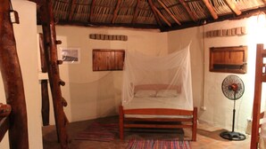 Una habitación con cama, ventilador y techo de paja.