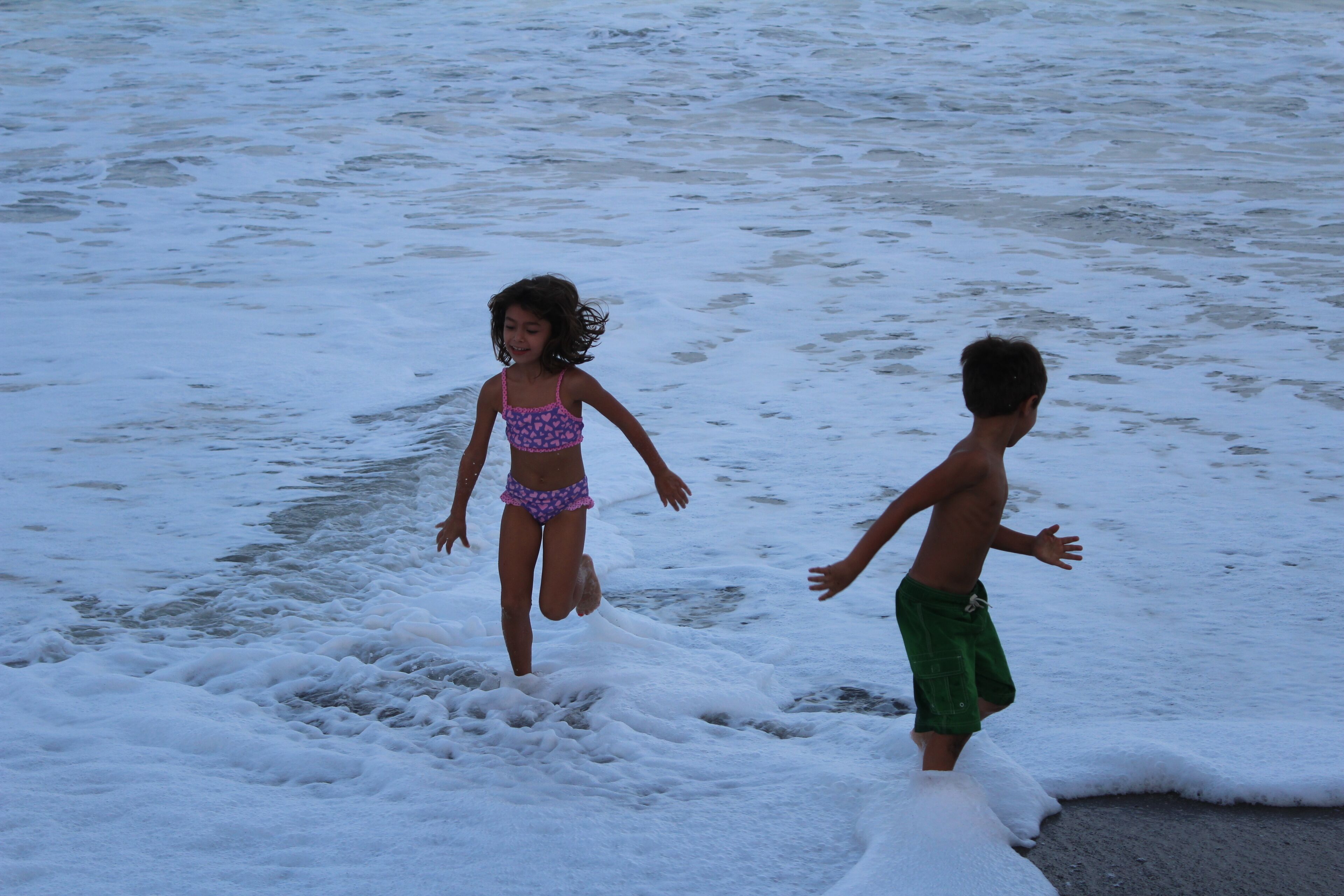 Two children playing in the water at the beach.