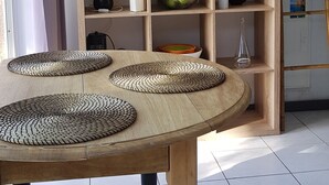 Taula de fusta amb suportes teixits, prestatge de fusta amb objectes decoratius i escala adossada a la paret.
