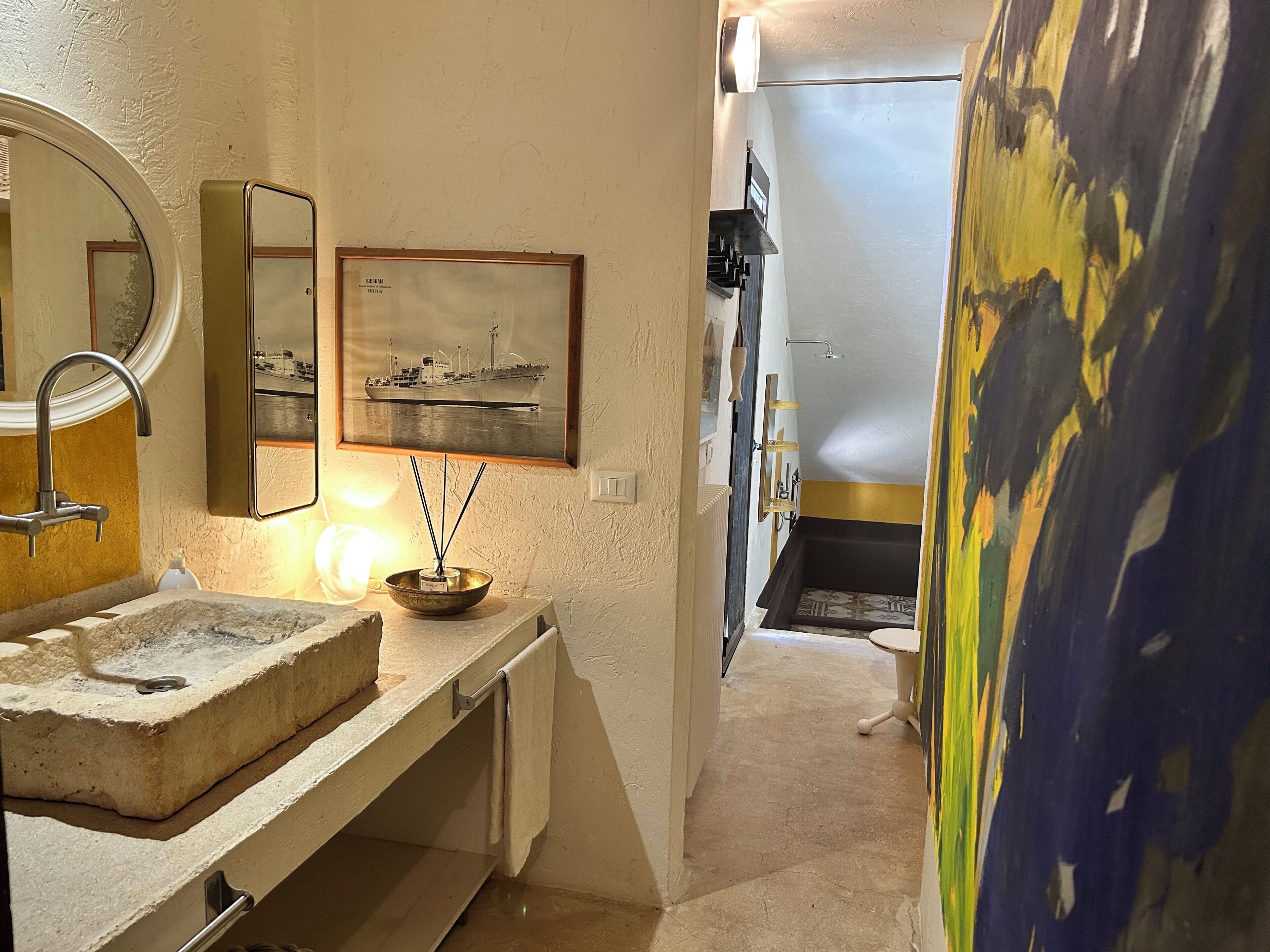 A bathroom with a sink, mirror, framed picture, and a shower area.