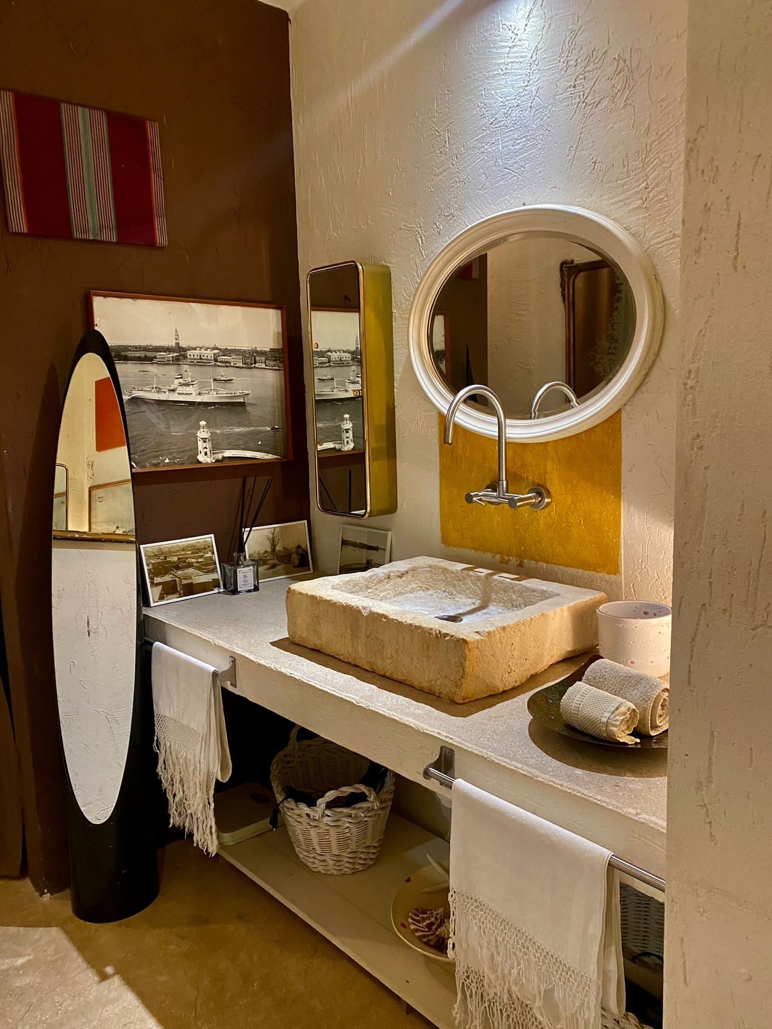 A bathroom with a large mirror, a sink, and a window with a view of a harbor.