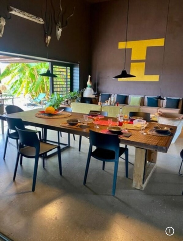 Uma zona de refeições moderna com uma mesa grande, cadeiras e vista para o exterior.