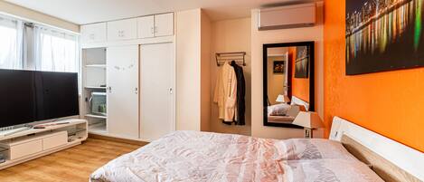 A modern bedroom with a bed, wardrobe, and a TV.