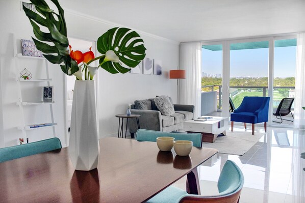 Un salon moderne comprenant un coin repas, un canapé, une table basse et offrant une vue sur la ville et la verdure.