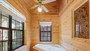 A wooden cabin interior with a wooden bathtub, a ceiling fan, and large windows. - Country Charm C - One of four Pet Friendly group cabins in Helen (Helen)