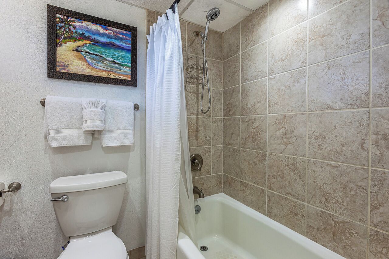 Un baño con inodoro, ducha con cortina y bañera.