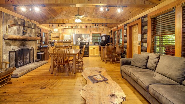 A rustic cabin interior with a dining area, wooden floors, a fireplace, and a sofa. - Adanaylah - A True Log Cabin Experience. Pet Friendly, too! (Hiawassee)