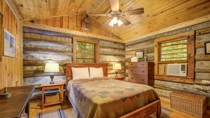 A log cabin bedroom with a wooden bed, two bedside tables with lamps, a dresser, a ceiling fan, and a window with blinds. - Adanaylah - A True Log Cabin Experience. Pet Friendly, too! (Hiawassee)