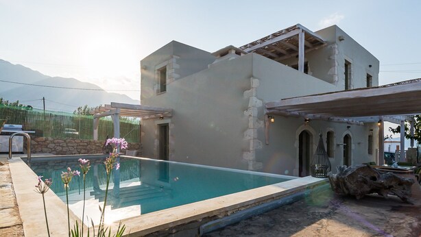 Una casa moderna con piscina, paredes de piedra y un patio de piedra.