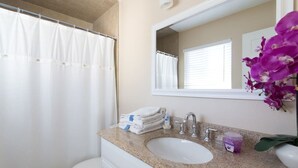 Un baño con inodoro blanco, lavabo con espejo y cortina de ducha.