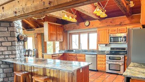 Una cocina rústica con armarios de madera, encimera de granito y pared de piedra.