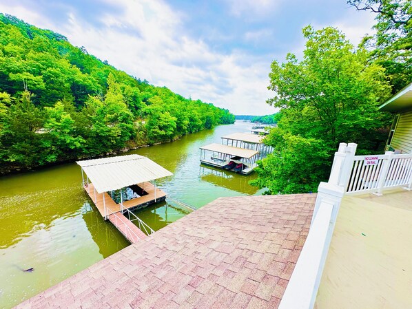 A riverside dock with a covered seating area and a white railing.