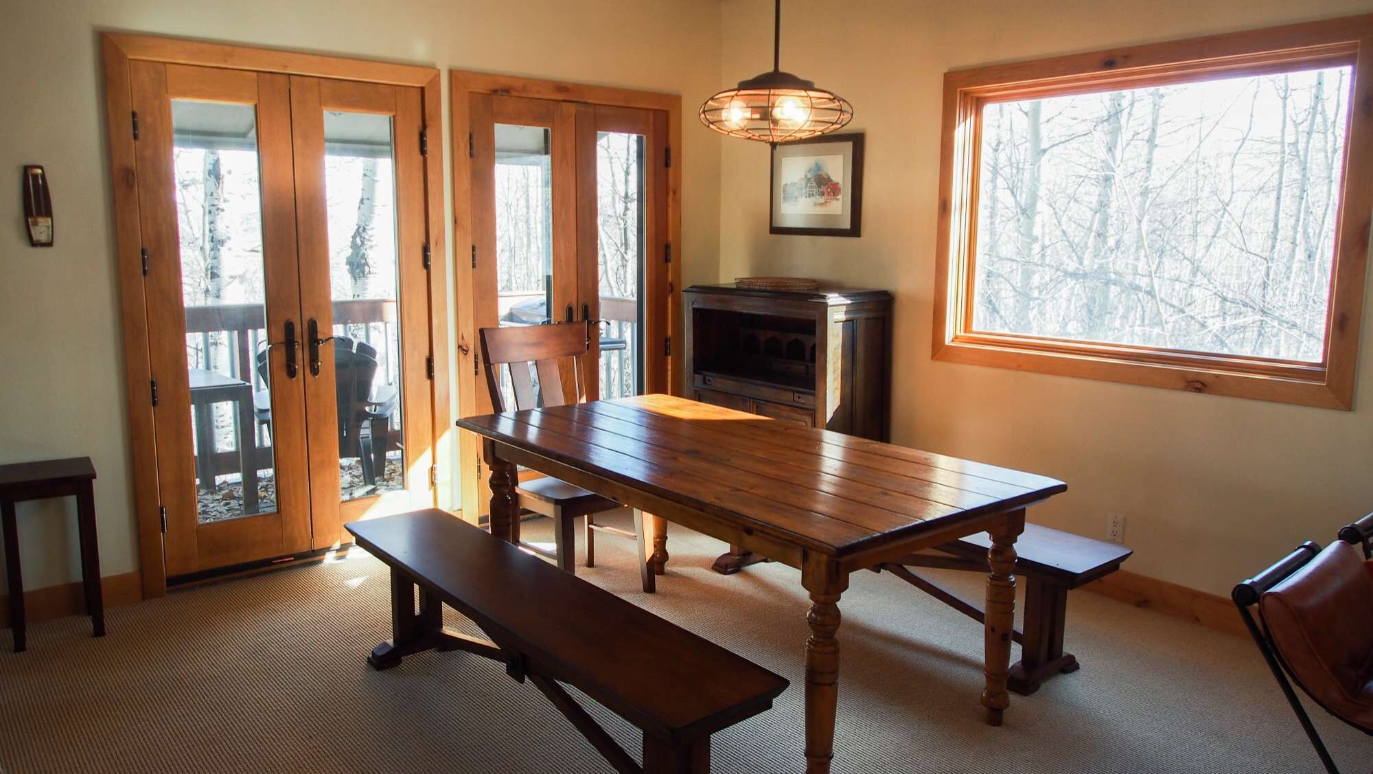 A dining area with a wooden table, benches, and a fireplace.