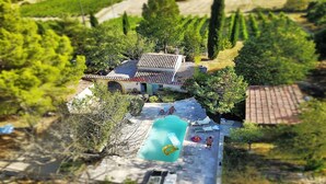 Vista aérea de una villa con piscina, rodeada de exuberante vegetación y un viñedo.
