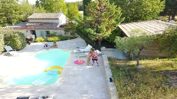Une piscine avec un toboggan, entourée de chaises longues et d’un petit flotteur gonflable.