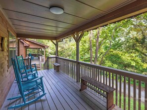 A wooden deck with a bench and rocking chairs, overlooking a forested area. - Country Charm B - Pet Friendly Cabin in city limits of Helen GA (Helen)