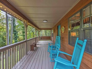 A wooden porch with a bench and blue chairs, overlooking a forested area. - Country Charm B - Pet Friendly Cabin in city limits of Helen GA (Helen)