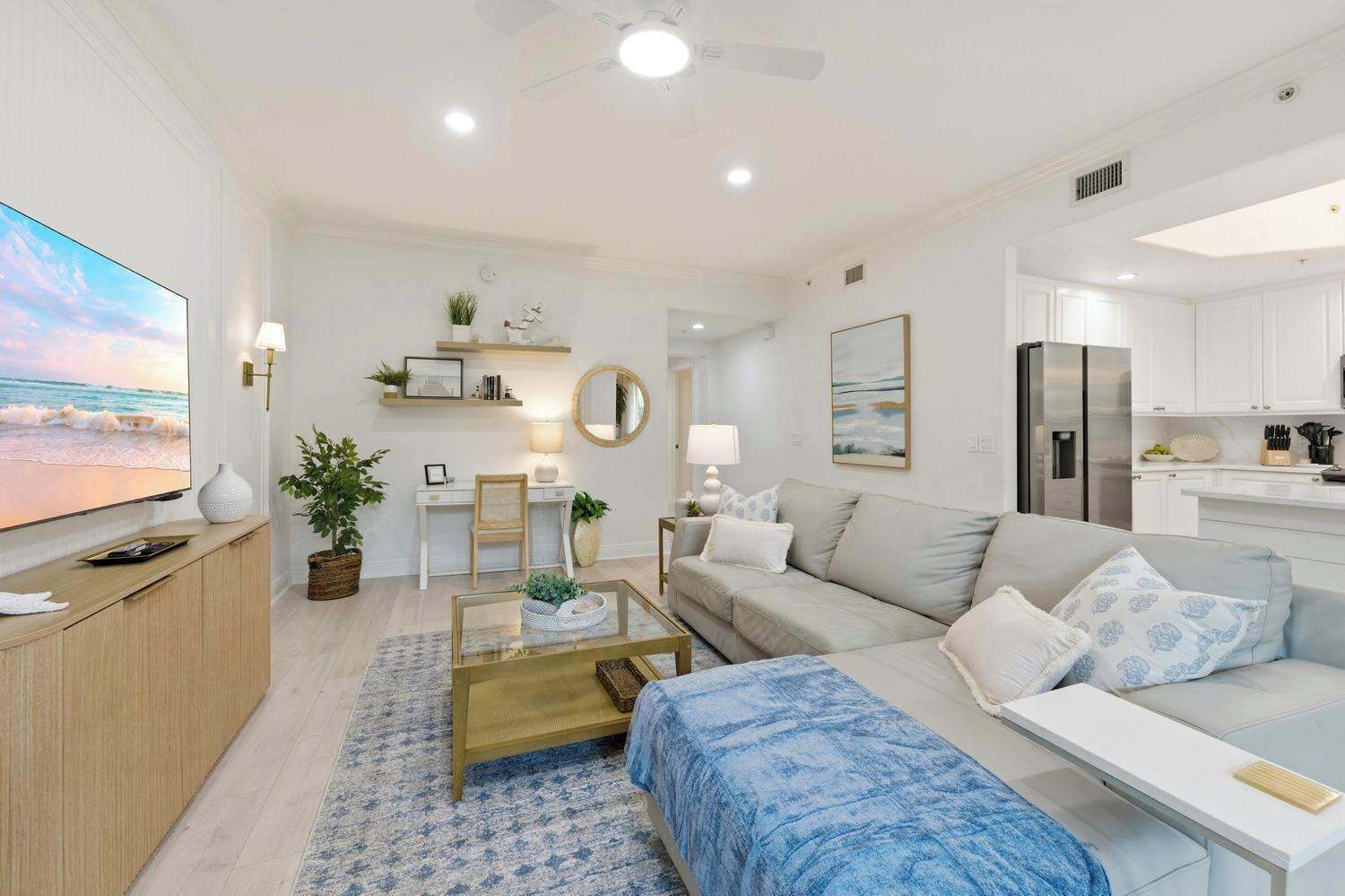 Una sala moderna con televisión, sofá, mesa de centro y zona de cocina.