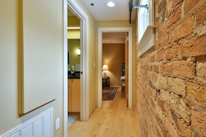 A narrow hallway with a brick wall on one side and a kitchen area on the other.