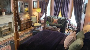 Un dormitorio tradicional con cama con dosel, un sofá, una silla y una mesita.