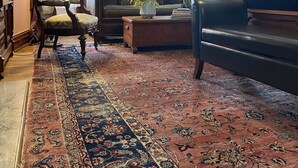 Un salón tradicional con alfombra estampada, un sofá, una silla y una lámpara.