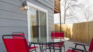Eine Terrasse im Freien mit einem Glastisch und vier roten Stühlen.