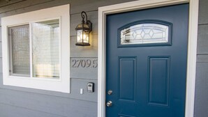A blue door with a glass panel and a number plaque reading "27095".
