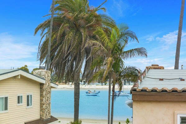 A beachfront property with a stone chimney, a pool, and a view of the beach.