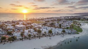 An aerial view of a coastal city with a beach, residential buildings, and a clear sky during sunset. - Beautiful Bayfront Condo with Water Views (San Diego)