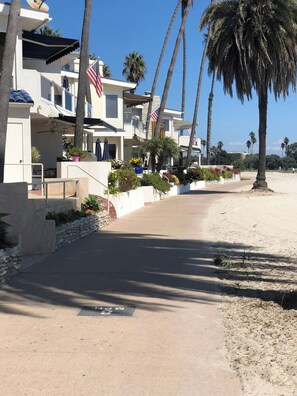 A coastal residential area with houses, palm trees, and a clear sky.