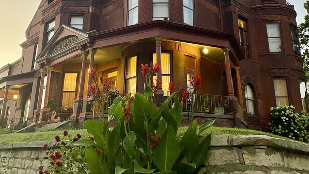 A large, historic building with a prominent corner turret and a wrap-around porch.