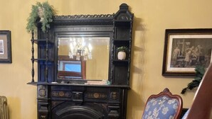 A traditional room with a fireplace, two upholstered chairs, a patterned rug, and a mirror on the wall.