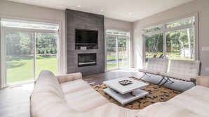 Ein modernes Wohnzimmer mit Kamin, großen Fenstern und einer Sitzecke.