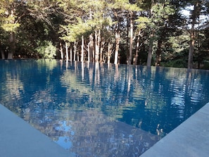 A rectangular swimming pool with clear blue water, surrounded by tall trees. - cool modern in east hampton , private , 5 nite min (East Hampton)