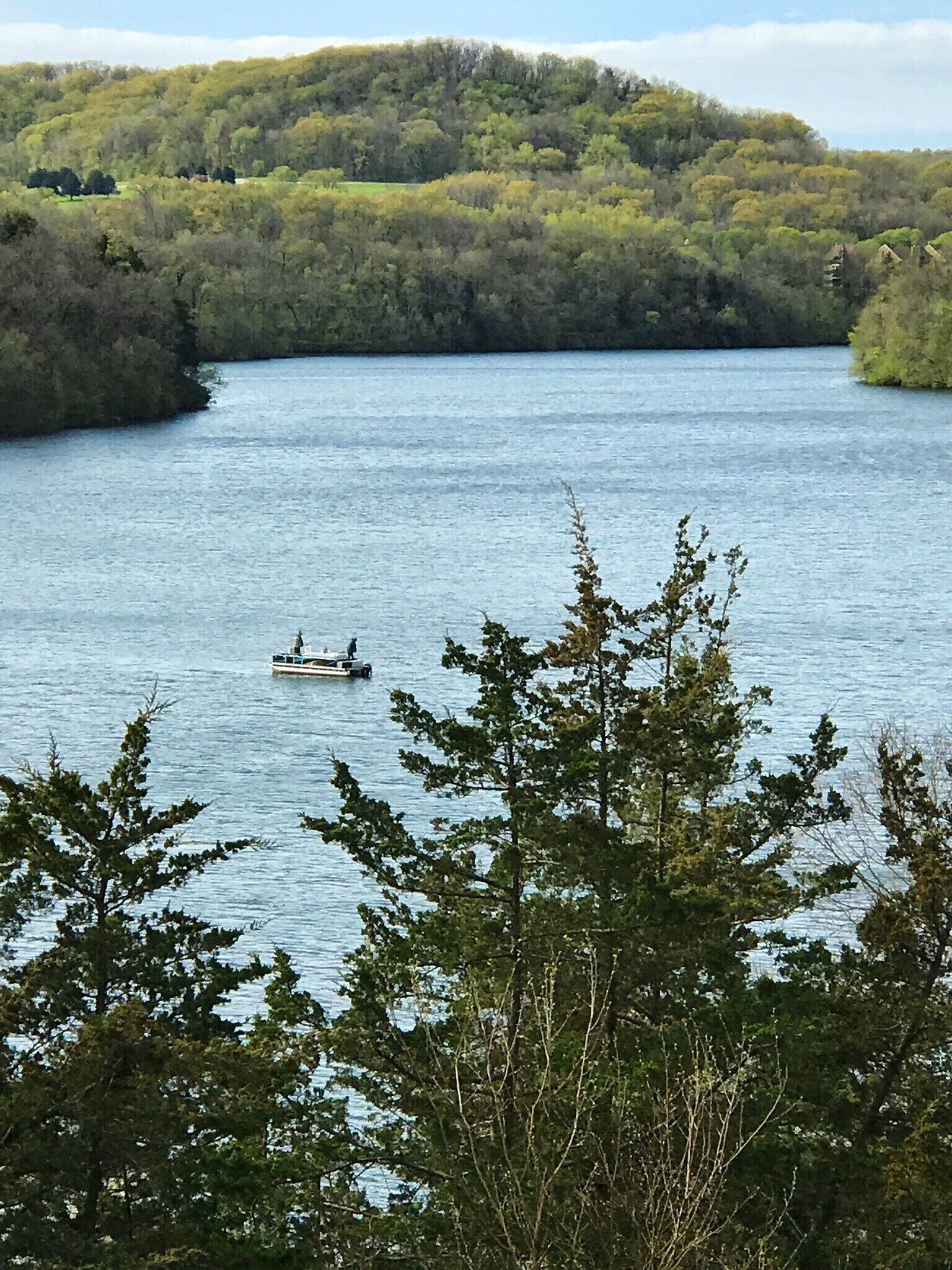 Un río tranquilo con barcos, rodeado de un bosque denso y colinas.