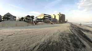 Una playa con edificios, incluyendo una construcción de varios pisos y una cabaña.