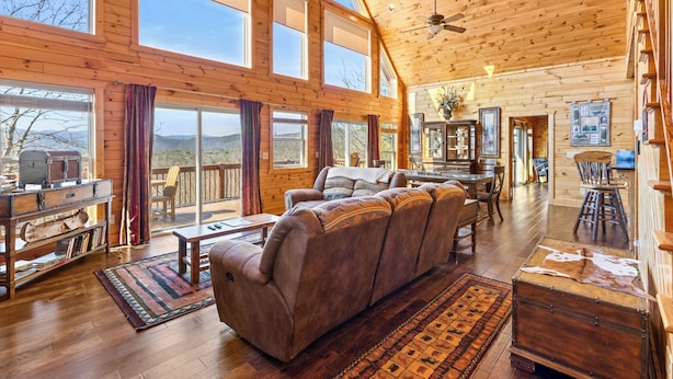 A spacious living area with a large sofa, wooden flooring, and a view of the outdoors.