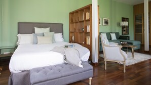 A bedroom with a large bed, a wooden bookshelf, a green sofa, and a chair.