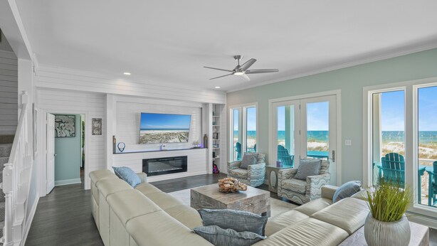 A spacious living room with a large beige sectional sofa, a fireplace, and a view of the beach. - Stunning Beachfront • Private • Remodeled • Game Room • 5BR • 200+5-Star Reviews (Gulf Shores)