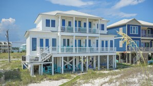 A two-story beach house with a balcony and outdoor seating area. - Stunning Beachfront • Private • Remodeled • Game Room • 5BR • 200+5-Star Reviews (Gulf Shores)