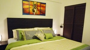 Un letto rifatto con biancheria verde, una testata scura e un quadro sopra.