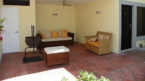 Un'ampia veranda con un divano in vimini, una panca imbottita e una poltrona in vimini.