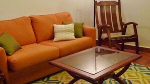 Un soggiorno con divano, tavolino da caffè, tappeto decorato e due quadri astratti alle pareti.