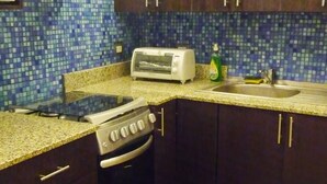 Una cucina con pensili scuri, un fornello, un tostapane e un lavandino.