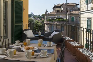 A balcony with a table set for breakfast, including cups, plates, and a croissant.