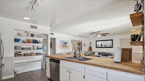 A modern kitchen with white cabinetry, a wooden countertop, and built-in shelves.
