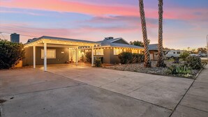 A single-story house with a covered porch, a garage, and a small garden with cacti and palm trees.