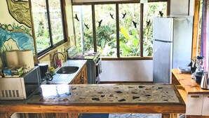 Une cuisine rustique dotée d’un grand îlot central, de tabourets de bar et d’un réfrigérateur.